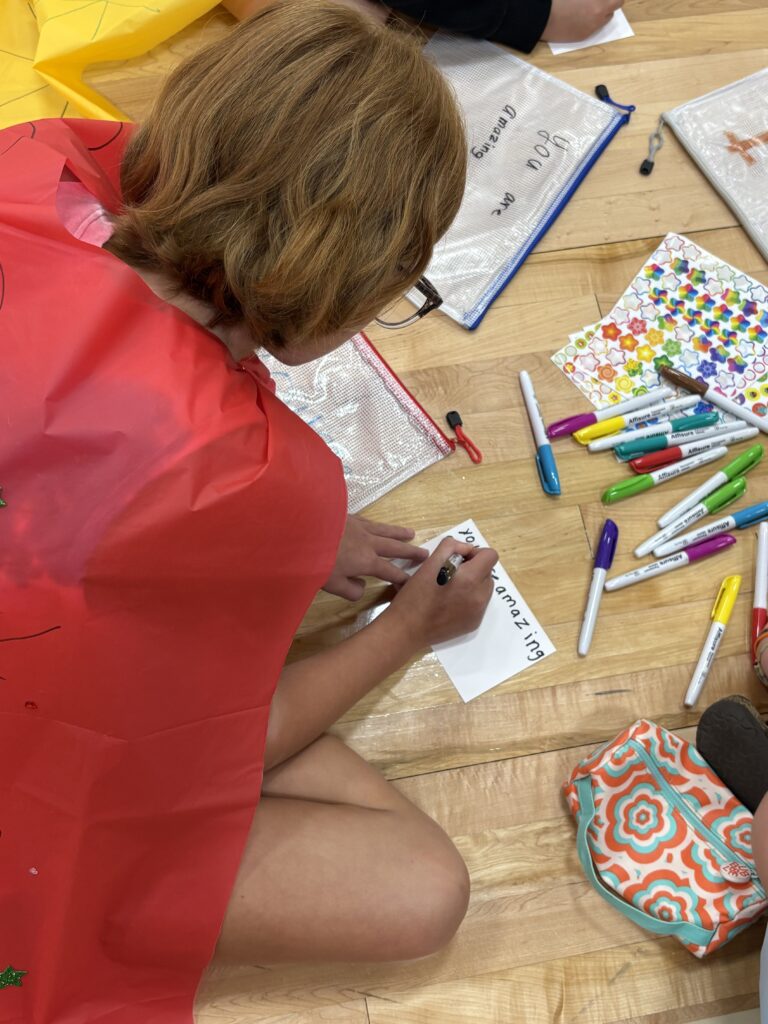 Kid creating positive bag and card: "You are amazing."
