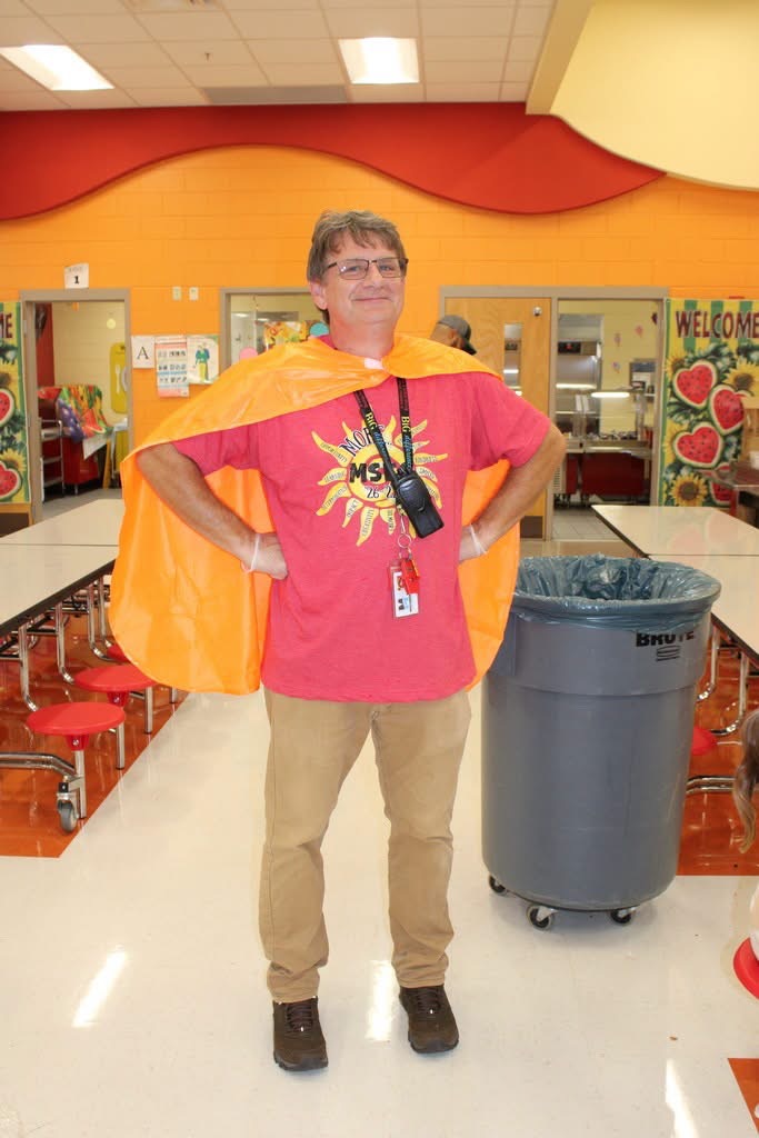 Principal in a Superhero stance wearing a superhero cape.